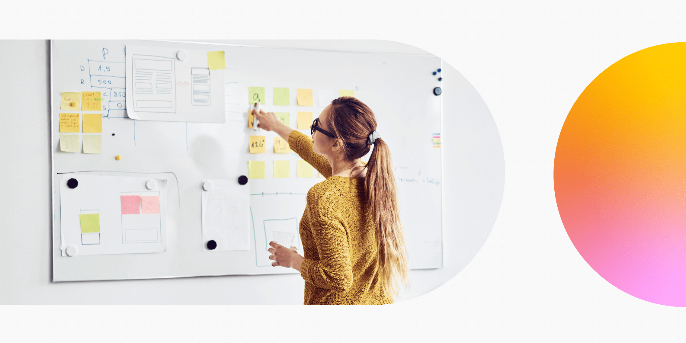 A person putting sticky notes on a whiteboard as part of a design process.